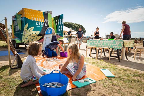Children with art activities next to the Creative Cabin vehicle