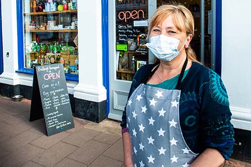 Shop staff with a face covering standing outside a gift shop
