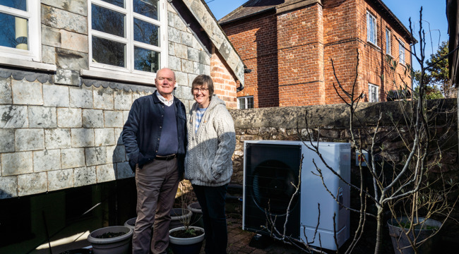 Photo of two people stood in a garden outside their house