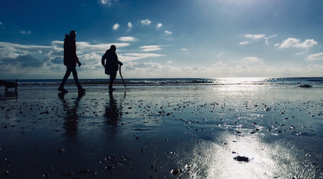 people walk on a sandy beach