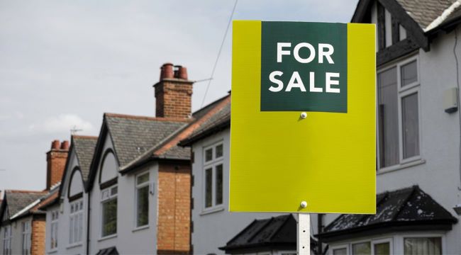 Photo of a for sale sign in front of six semi-detached houses with rendered exteriors