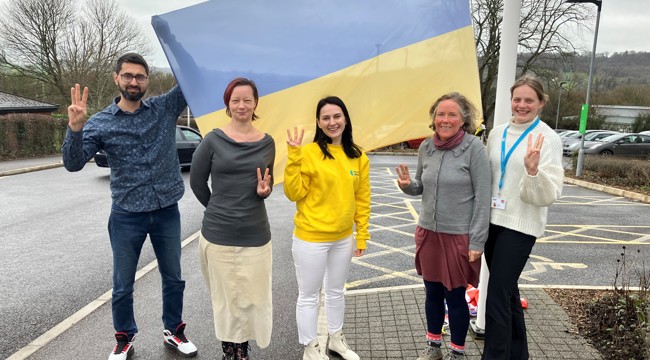 The Homes for Ukraine team with the Ukranian flag, outside Blackdown House