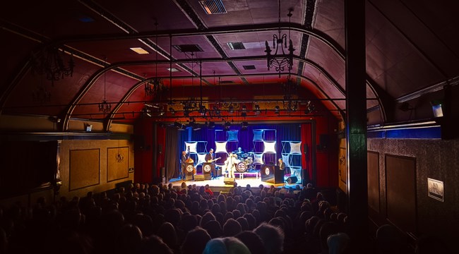 The auditorium at the theatre full and a band, brightly lit on stage