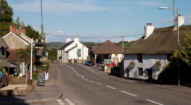 Photo of Colyford, with a thatched cottage next to a road