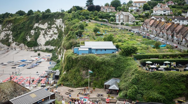 view of beach with crowd and upturned boat in foreground