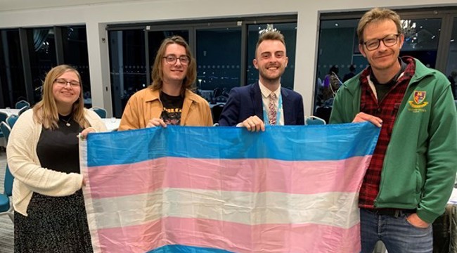 Councillor Jake Bonetta (second to right) who proposed the motion which was seconded by Councillor Joe Whibley (far right) stand holding the trans flag